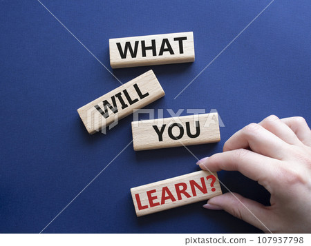 What will you learn symbol. Concept word. What will you learn on wooden blocks. Beautiful deep blue background. Businessman hand. Business and What will you learn concept. Copy space 107937798