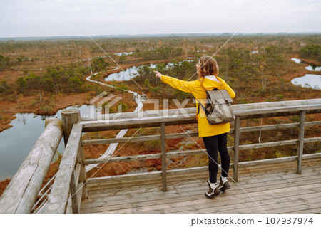 Young woman looks at amazing nature on observation deck. Tourist enjoys a view of magical swamps. 107937974