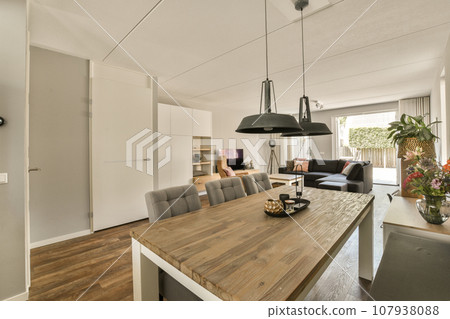 a dining room with wood flooring and white walls in an open living area, including a large wooden table surrounded by grey chairs a dining room with wood flooring and white walls in an open living area, including a large wooden table surrounded by grey chairs 107938088