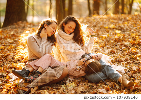 The homosexual family playing with her daughter in the autumn forest. The adventure is more fun. The homosexual family playing with her daughter in the autumn forest. The adventure is more fun. 107939146