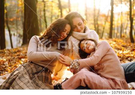 The homosexual family playing with her daughter in the autumn forest. The adventure is more fun. The homosexual family playing with her daughter in the autumn forest. The adventure is more fun. 107939150