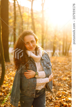 Stylish woman posing in the autumn forest at sunset. Lifestyle. High fashion portrait. 107939176