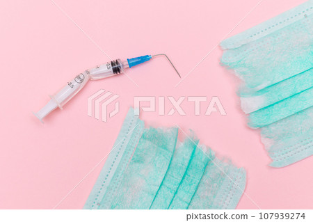 Broken Medical Syringe and Torn Medical Face Mask on the Pink Background 107939274