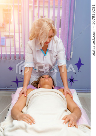 Masseur woman massages her shoulders. Woman getting a massage at the spa 107939281