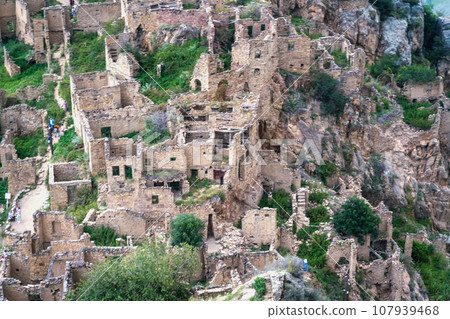 Dagestan Gamsutl. Ancient ghost town of Gamsutl old stone houses in abandoned Gamsutl mountain village in Dagestan, Abandoned etnic aul, summer landscape. 107939468