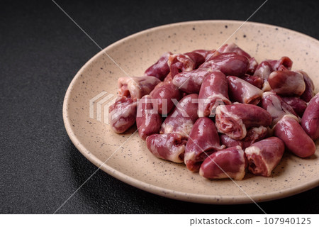 Fresh raw chicken, turkey or duck hearts on a ceramic plate with salt and spices 107940125