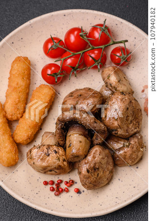 Delicious juicy whole champignons baked on the grill with salt and spices 107940182