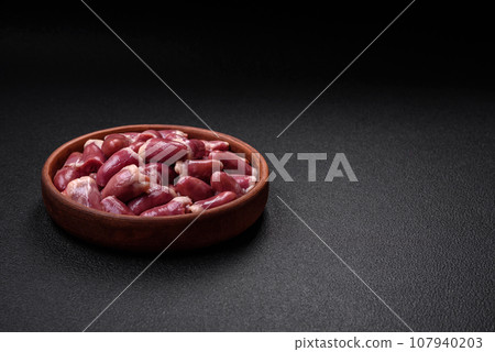 Fresh raw chicken, turkey or duck hearts on a ceramic plate with salt and spices 107940203