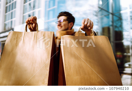 Stylish man with paper packages after shopping. Sale, consumerist, lifestyle concept. Stylish man with paper packages after shopping. Sale, consumerist, lifestyle concept. 107940210