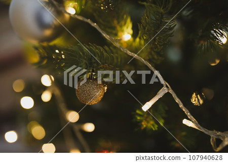 Christmas and New years eve Background. Holiday Template with Christmas toy on fir tree. Web banner with copy space for design. Close up of balls on christmas tree. Bokeh garlands in the background Christmas and New years eve Background. Holiday Template with Christmas toy on fir tree. Web banner with copy space for design. Close up of balls on christmas tree. Bokeh garlands in the background 107940628