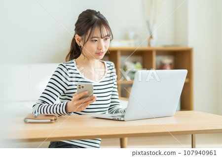 在智能手機上使用兩步驗證的女性 操作 PC 的女性 遠程辦公的年輕女性 在智能手機上使用兩步驗證的女性 操作 PC 的女性 遠程辦公的年輕女性 107940961