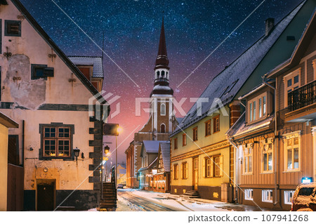 Parnu, Estonia. Night View Of Kuninga Street With Old Houses In Evening Night Illuminations. Amazing Bold Bright Blue Starry Sky Gradient. View Of Lutheran Church Of St. Elizabeth On Background 107941268