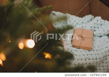 Christmas gift wrapped in craft paper under a tree. New Year card 107941289
