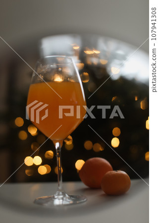 tangerine or orange juice with tangerines on the Christmas tree background  107941308