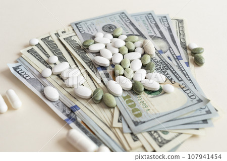 Closeup Many Dollar Money Banknotes And Different Pills Or Tablets. Expensive Medicine And Healthcare Insurances. Inflation. Pharmaceutical Industry And Big Pharma. Horizontal Plane 107941454