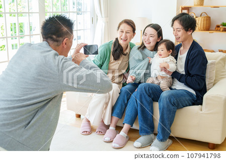 Three generations of family taking commemorative photos with smartphones Three generations of family taking commemorative photos with smartphones 107941798