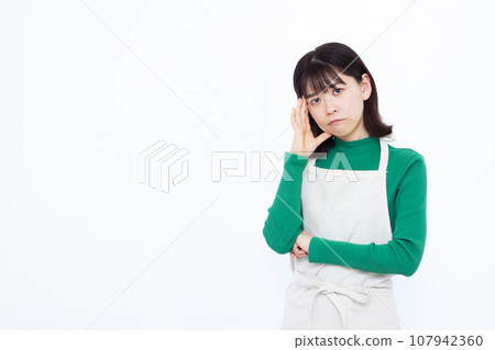 A housewife in her 30s worries while holding her head in front of a white background A housewife in her 30s worries while holding her head in front of a white background 107942360