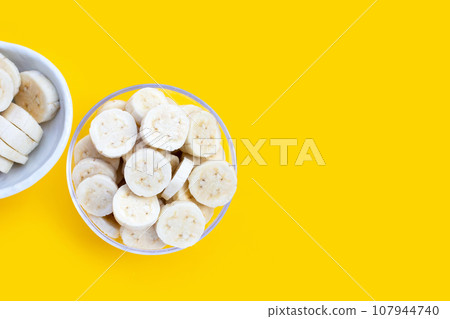 Banana slices in bowl on yellow background. Banana slices in bowl on yellow background. 107944740