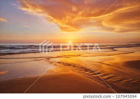 Atlantic ocean sunset with surging waves at Fonte da Telha beach, Costa da Caparica, Portugal 107945094
