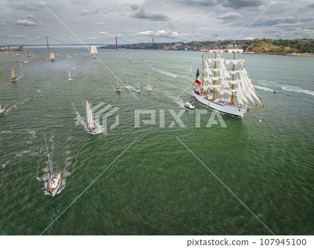 Aerial drone view of tall ships with sails sailing in Tagus river towards the Atlantic ocean in Lisbon, Portugal 107945100