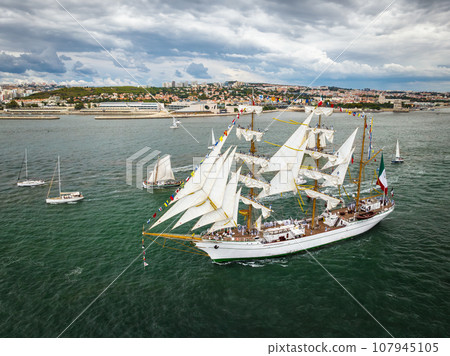 Aerial drone view of tall ships with sails sailing in Tagus river towards the Atlantic ocean in Lisbon, Portugal 107945105