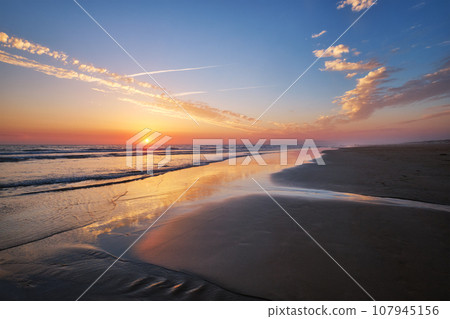 Atlantic ocean sunset with surging waves at Fonte da Telha beach, Costa da Caparica, Portugal 107945156