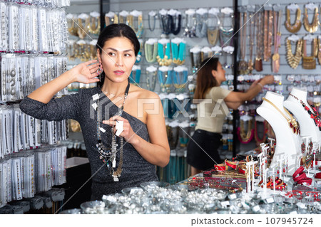 Interested asian woman choosing bijouterie in jewelry store Interested asian woman choosing bijouterie in jewelry store 107945724