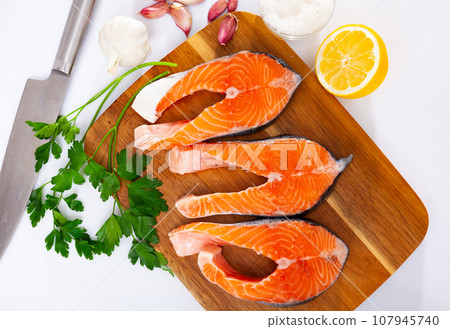 Fresh sliced salmon on wooden cutting board, over white background Fresh sliced salmon on wooden cutting board, over white background 107945740