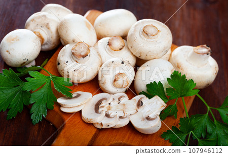 Champignons mushrooms on wooden surface with greens Champignons mushrooms on wooden surface with greens 107946112