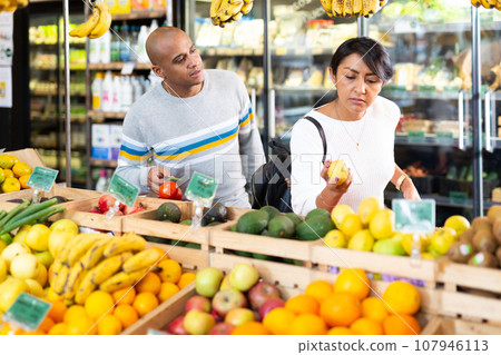 Family couple looking for fresh fruits and vegetables in food store Family couple looking for fresh fruits and vegetables in food store 107946113