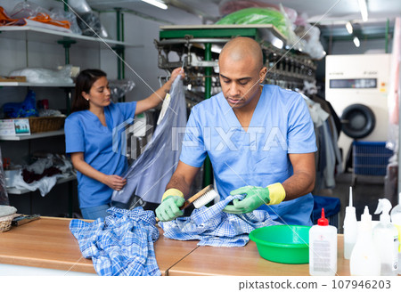 Portrait of male laundry worker examining clean garments 107946203