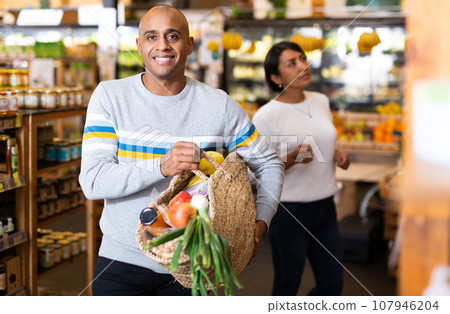 Shopper with bag of groceries and vegetables at supermarket 107946204
