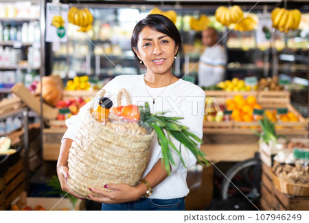 Satisfied hispanic woman with purchases in supermarket 107946249