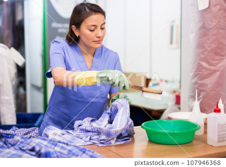 Focused woman drycleaner removing spots and stains 107946368