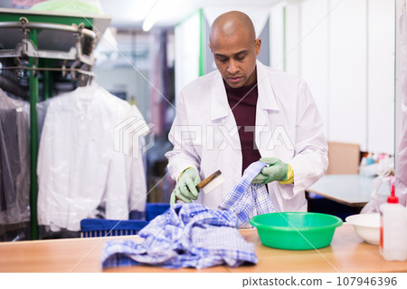 Focused man drycleaner removing spots and stains 107946396