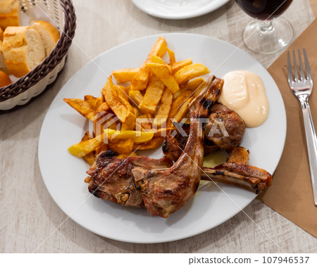 Baked lamb ribs with french fries and aioli sauce Baked lamb ribs with french fries and aioli sauce 107946537