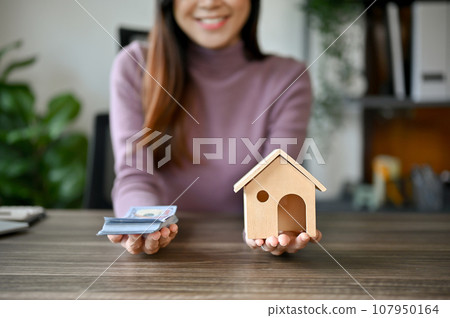 A young Asian girl with house model planning on buying her house 107950164