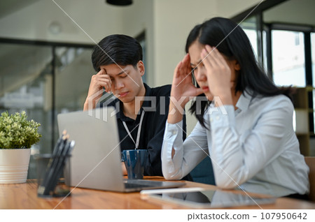 Two serious Asian office workers are focusing on their co-project together 107950642