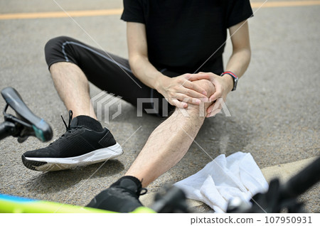 Close-up image of an injured male cyclist fell off the bike while biking along country roads. Close-up image of an injured male cyclist fell off the bike while biking along country roads. 107950931