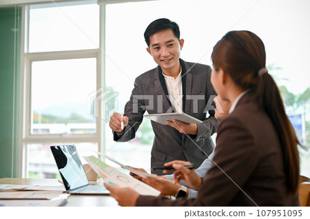 A professional Asian male boss sharing his ideas and discussing work with his employees 107951095