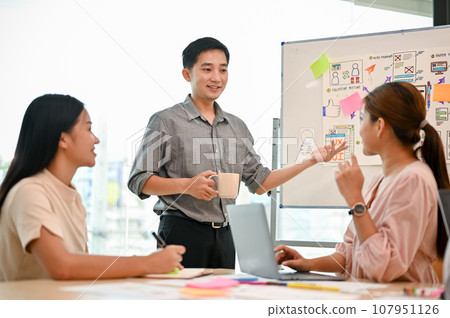A professional Asian male tech developer is presenting his project to his colleagues in the meeting. A professional Asian male tech developer is presenting his project to his colleagues in the meeting. 107951126
