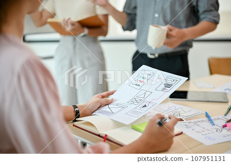 Close-up image of a professional female UI developer is in the meeting with her colleagues Close-up image of a professional female UI developer is in the meeting with her colleagues 107951131