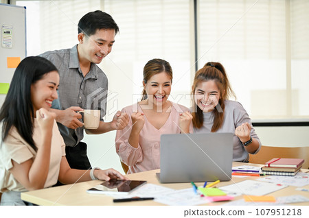 A group of cheerful Asian tech developers celebrating their new project success together A group of cheerful Asian tech developers celebrating their new project success together 107951218