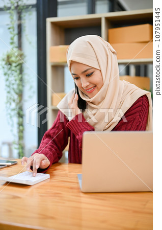 A beautiful SME online business owner dealing business over the phone with her supplier. A beautiful SME online business owner dealing business over the phone with her supplier. 107951445