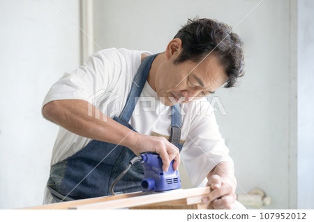 Man using sander DIY at home 107952012
