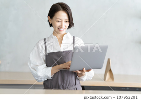 A cafe clerk checking orders on a computer A cafe clerk checking orders on a computer 107952291