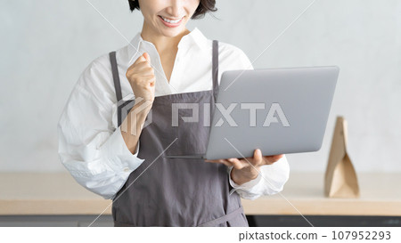 A cafe clerk checking orders on a computer 107952293