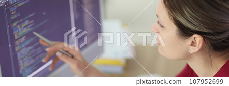 Woman checks code pointing pen to screen of computer 107952699