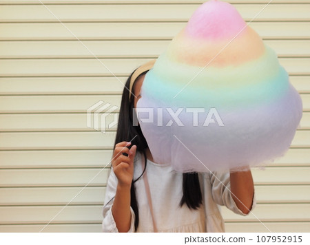 Girl eating cotton candy as big as her face Girl eating cotton candy as big as her face 107952915