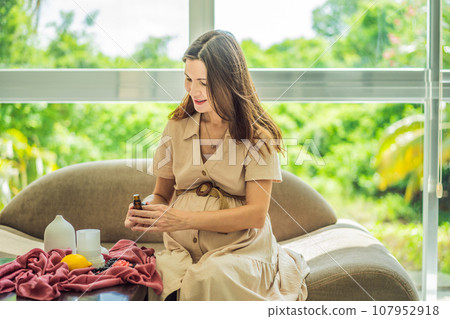 A serene moment captured as a pregnant woman after 40 embraces the soothing benefits of aroma oils and an aroma diffuser, enhancing her pregnancy journey with relaxation and tranquility 107952918